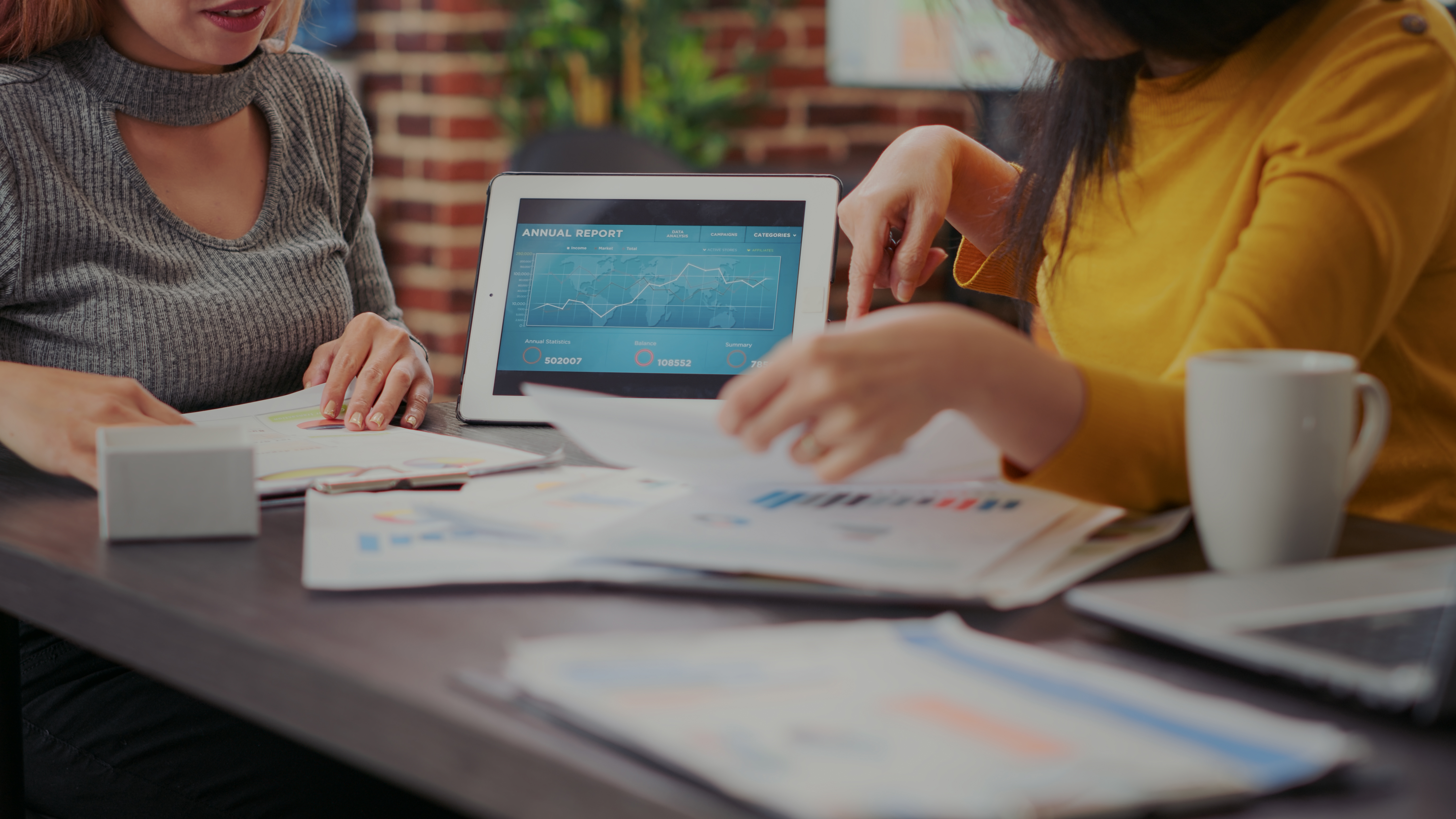 mujeres-analizando-informe-financiero-en-tableta-digital-trabajando-en-el-crecimiento-empresarial-companeros-de-trabajo-que-utilizan-el-analisis-de-informacion-de-ventas-para-planificar-la-inversion-par